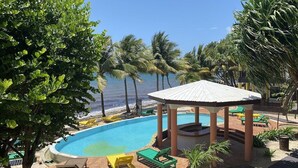 A pool area with lounge chairs, a gazebo, and palm trees.