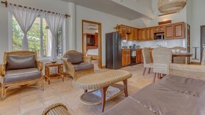 A spacious living area with wicker furniture, a kitchen with wooden cabinets, and a dining area with wicker chairs.