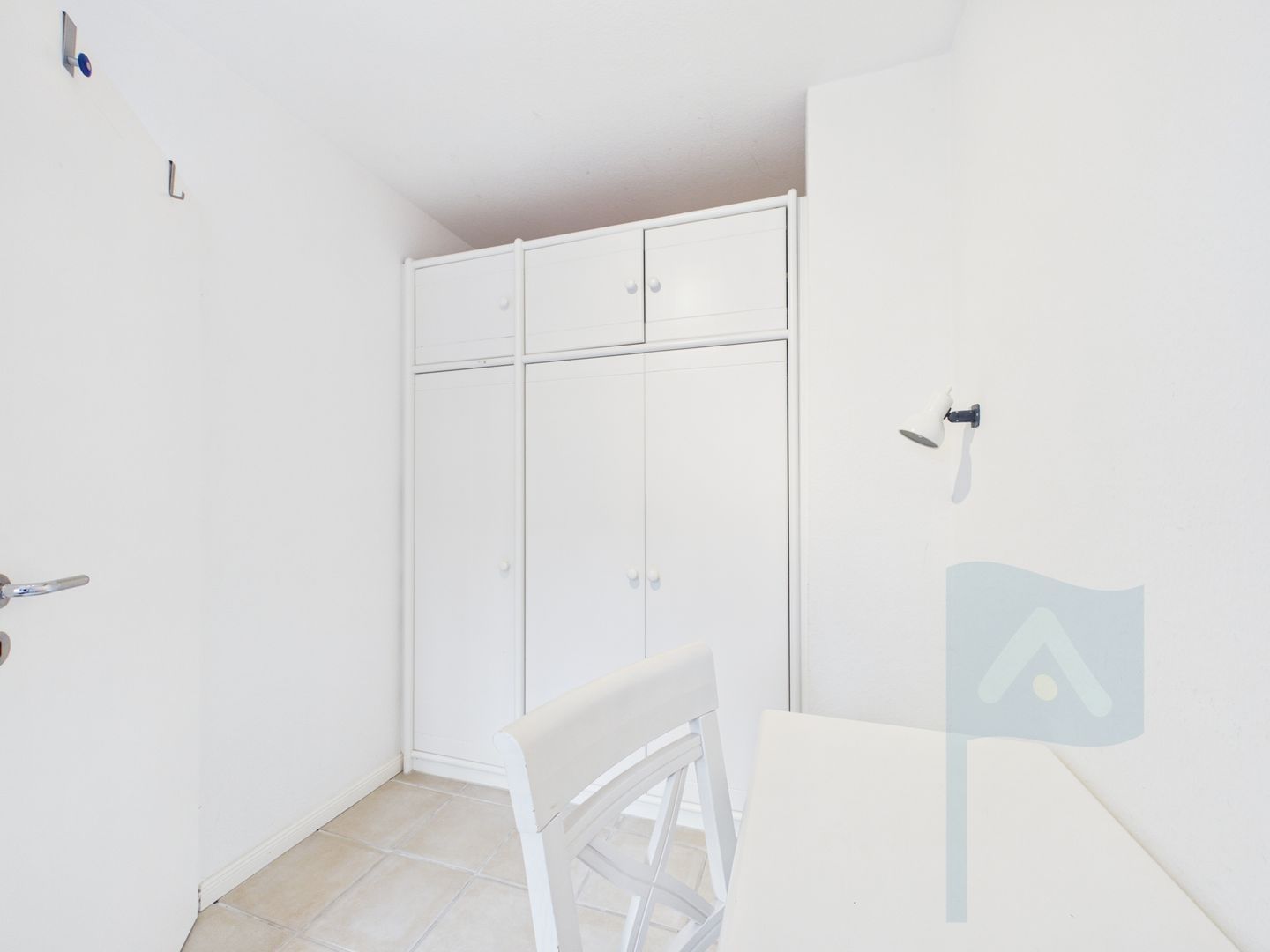 Ein Zimmer mit einem weißen Kleiderschrank, einem weißen Stuhl und einem weißen Tisch.