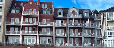 Un hôtel à plusieurs étages, doté de balcons et d’une façade en briques, avec un ciel dégagé.