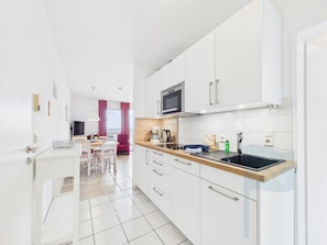 Une cuisine moderne avec des meubles blancs, un four à micro-ondes et un évier.