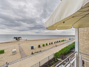 A beach view with a walkway, beach chairs, and a pier.