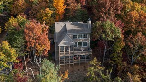 Une maison à deux étages, entourée d’un feuillage automnal.