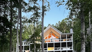 Et moderne hus med stor terrasse, omgivet af træer og en stenede sti.