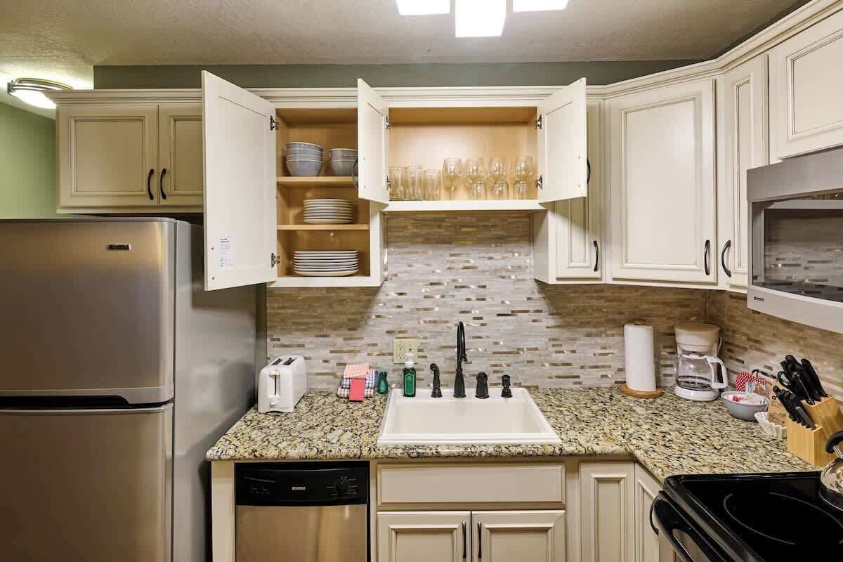 A kitchen with a stainless steel refrigerator, a granite countertop, a built-in dishwasher, and a double sink.
