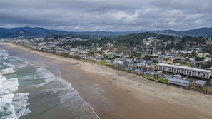 Une ville côtière avec une plage, des maisons et un grand bâtiment doté d’un toit plat.