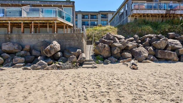 A beachfront hotel with a modern design, featuring a prominent balcony and a view of the ocean.