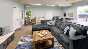 A living room with a sofa, coffee table, and a ping pong table.
