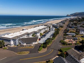 A coastal town with a beach, a parking lot, and a building with a sign that reads 'Surfside Plaza.'