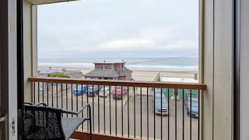 Enjoy the ocean view from this balcony with a chair and a view of the beach.