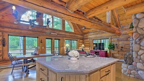 A spacious kitchen with a large island, wooden ceiling beams, and a stone accent wall.