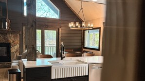 Une cuisine moderne dotée d’un îlot central, de planchers en bois et d’une cheminée en pierre.