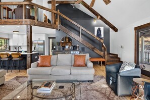 Un vaste espace de vie doté d’un haut plafond, d’un escalier, d’une cuisine et d’un coin repas.
