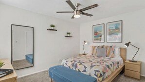 A bedroom with a bed, a ceiling fan, bedside tables, a mirror, and artwork on the wall. - Chaparral Charmer | 3BR | Pool | Bikes | King bed! (Scottsdale)