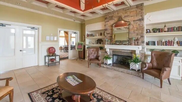 A spacious living room with a fireplace, leather chairs, a coffee table, and a bookshelf. - Modern Pool Villa on Guard Gated Golf Community with Conservation Views (Davenport)