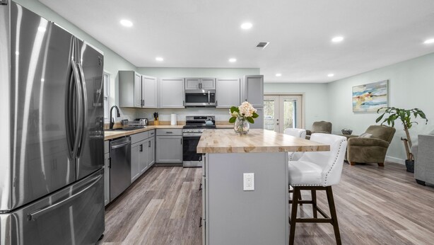 Una cucina moderna con elettrodomestici in acciaio inossidabile, un'isola in legno e mobili chiari.