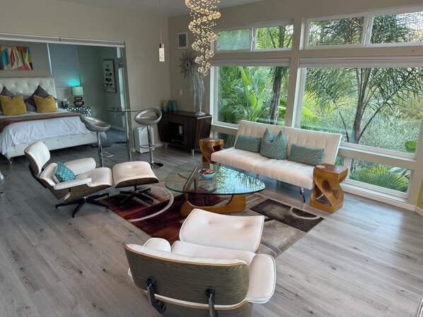 A modern living room with a glass coffee table, white sofas, and a large window with a view of greenery. - Private Luxury Suite with Views Near SF & Wine Country (San Rafael)