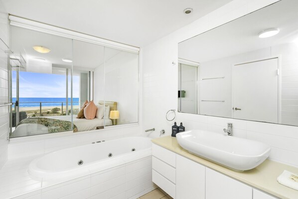 A modern bathroom with a large bathtub, a double sink, and a large mirror.