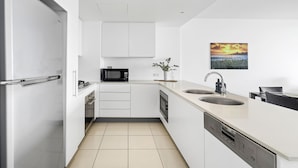 A modern kitchen with white cabinetry, a microwave, a sink, and a dishwasher. - Kirra Beach 506 Pure Ocean Views (Coolangatta)