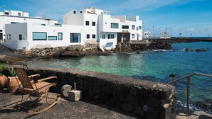 A coastal building with a stone wall and a clear view of the sea. - Lanzahost Villa Mimosa (Punta Mujeres)