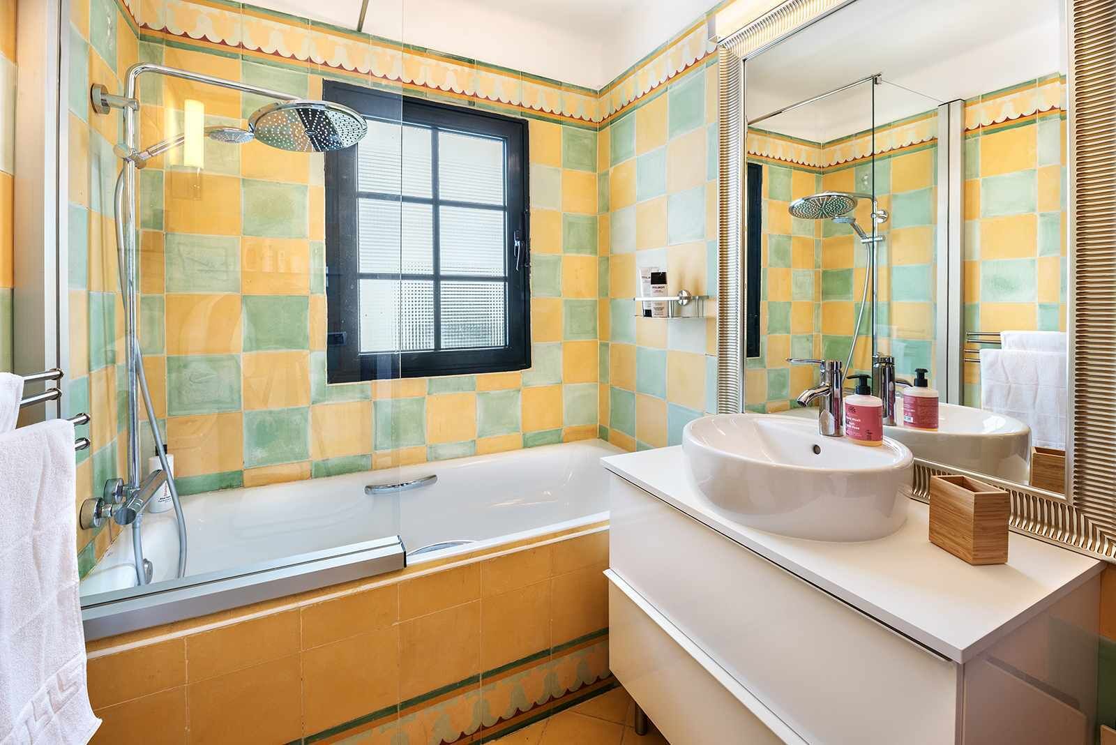Een badkamer met een bad, douche, wastafel en raam.