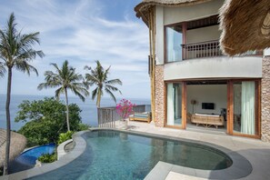 Un resort con piscina, balcón con vistas al mar y exuberante vegetación tropical.