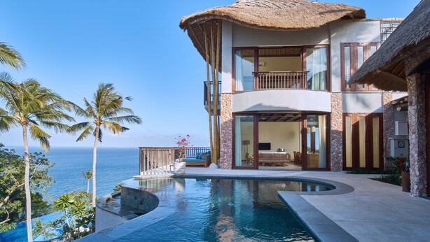 Una casa de dos pisos con piscina, balcón y vista al océano.