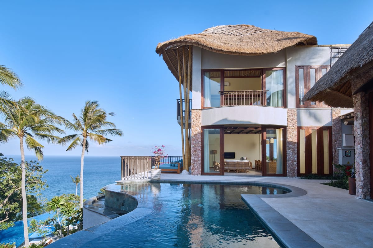 A two-story house with a pool, a balcony, and a view of the ocean.