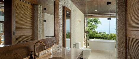 A modern bathroom with a large mirror, a sink, and a bathtub.