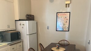 Une cuisine compacte comprenant une table à manger, des chaises, un réfrigérateur, un four à micro-ondes et des placards.