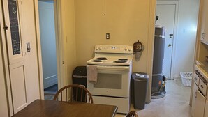 Une cuisine de taille réduite équipée d’une cuisinière, d’un four et d’une table à manger avec des chaises.