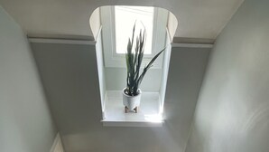 Een trap met houten treden en witte leuningen, die uitkomt op een plateau met een bloempot.