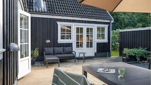 A cozy outdoor seating area with a sofa, table, and chairs under a large umbrella.
