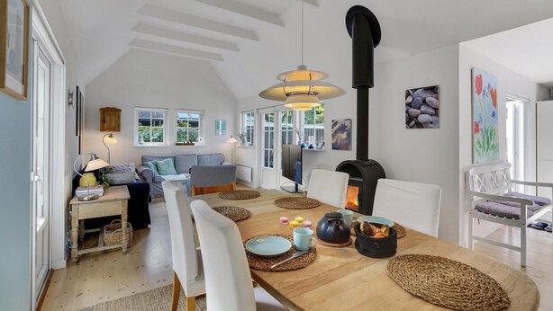 A cozy, well-lit dining area with a wooden table, white chairs, and a central fireplace.