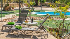 A poolside area with lounge chairs, a table with drinks, and a small pool.