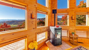 Eine Holzhütte mit mehreren Fenstern, einem Holzofen und Blick auf die Berge.