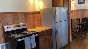 A kitchen with wooden cabinets, a stainless steel stove, a refrigerator, and a wooden countertop. - One Bedroom Cottage (Half Moon Bay)