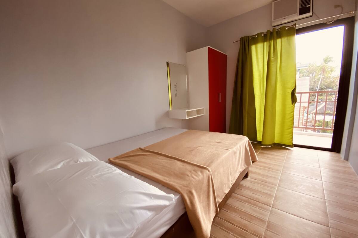 A bedroom with a bed, a wardrobe, and a window with curtains.