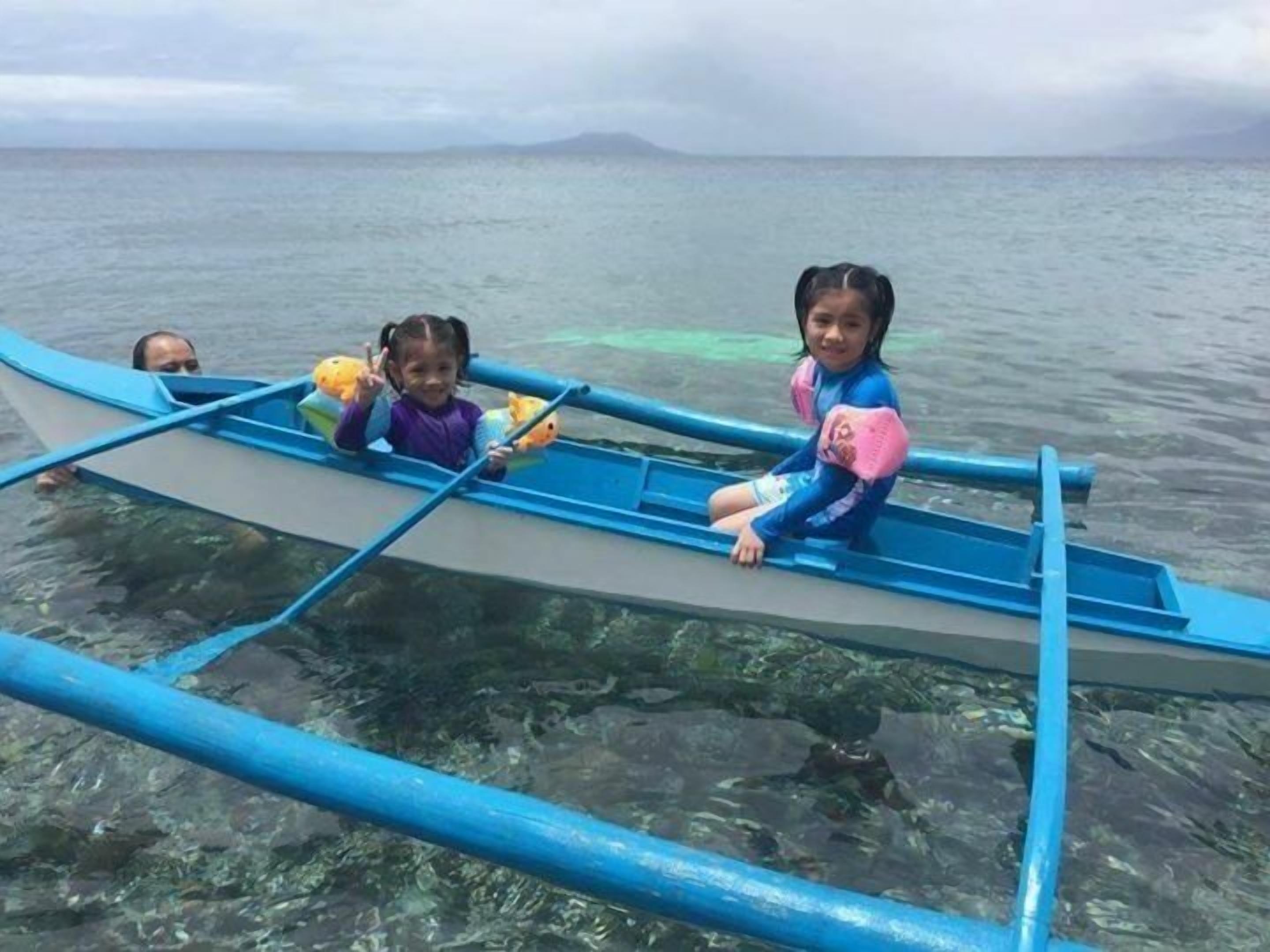 Una lancha con dos niños y un adulto, flotando sobre aguas cristalinas.
