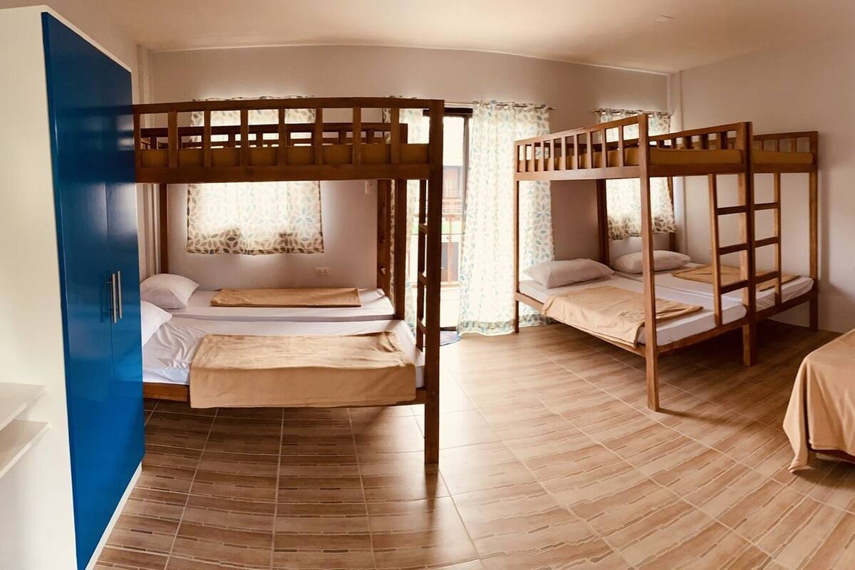 A room with bunk beds, a small kitchen area, and a bathroom with a shower.