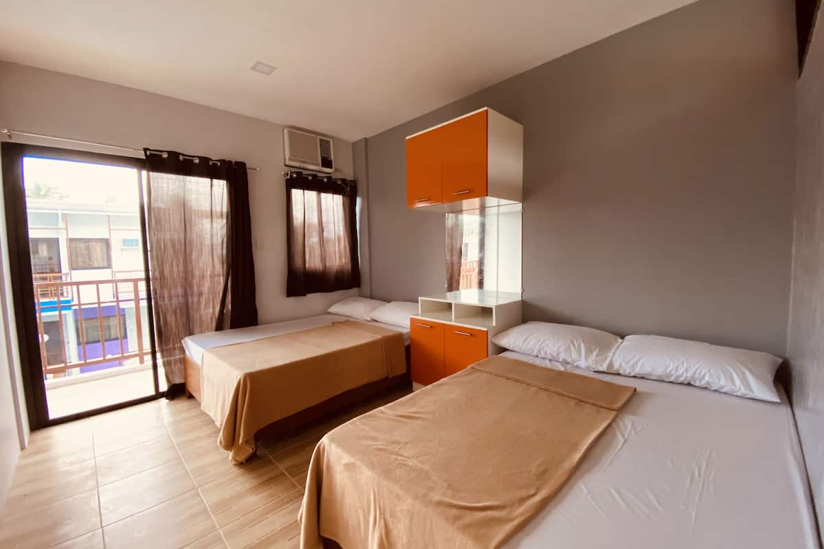 A hotel room with two beds, a balcony, and a view of the outside.