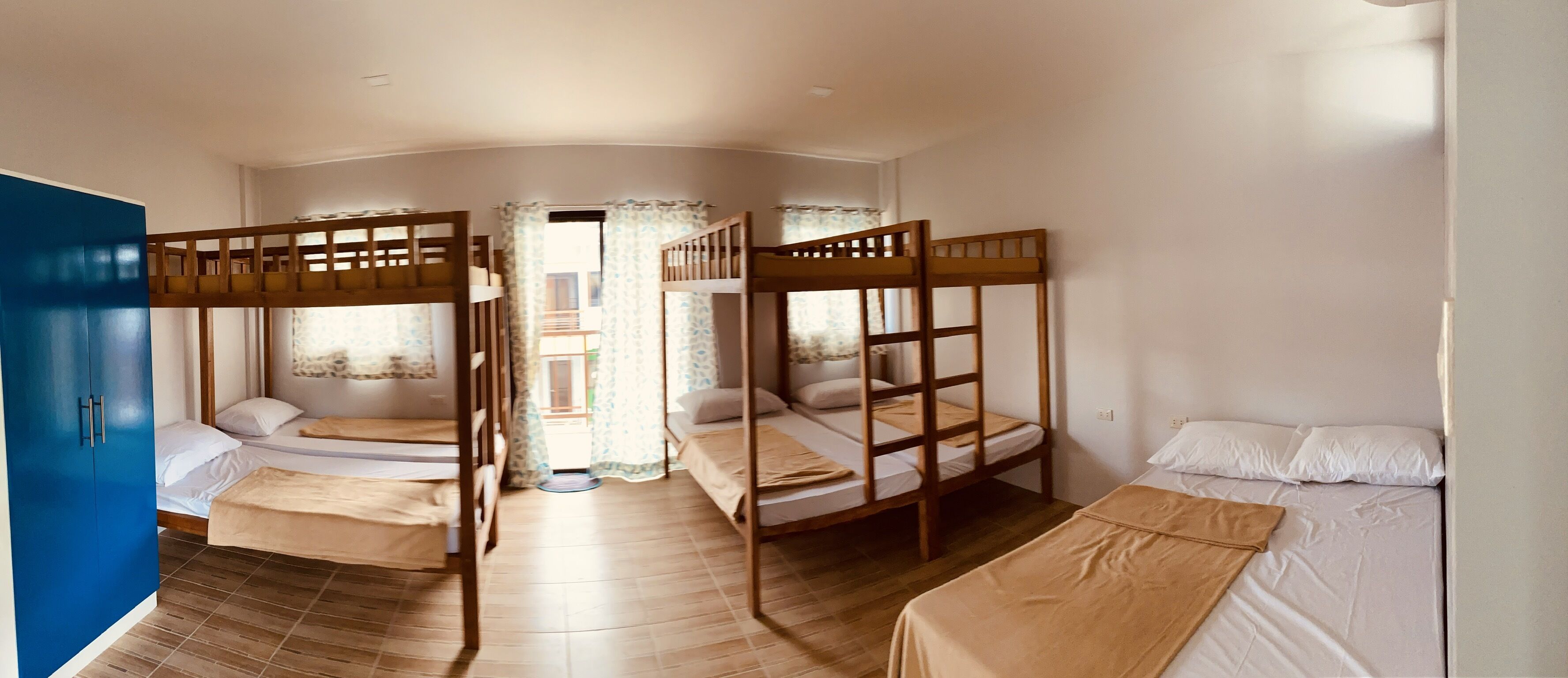 Una habitación con literas, un armario azul y una ventana con cortinas.