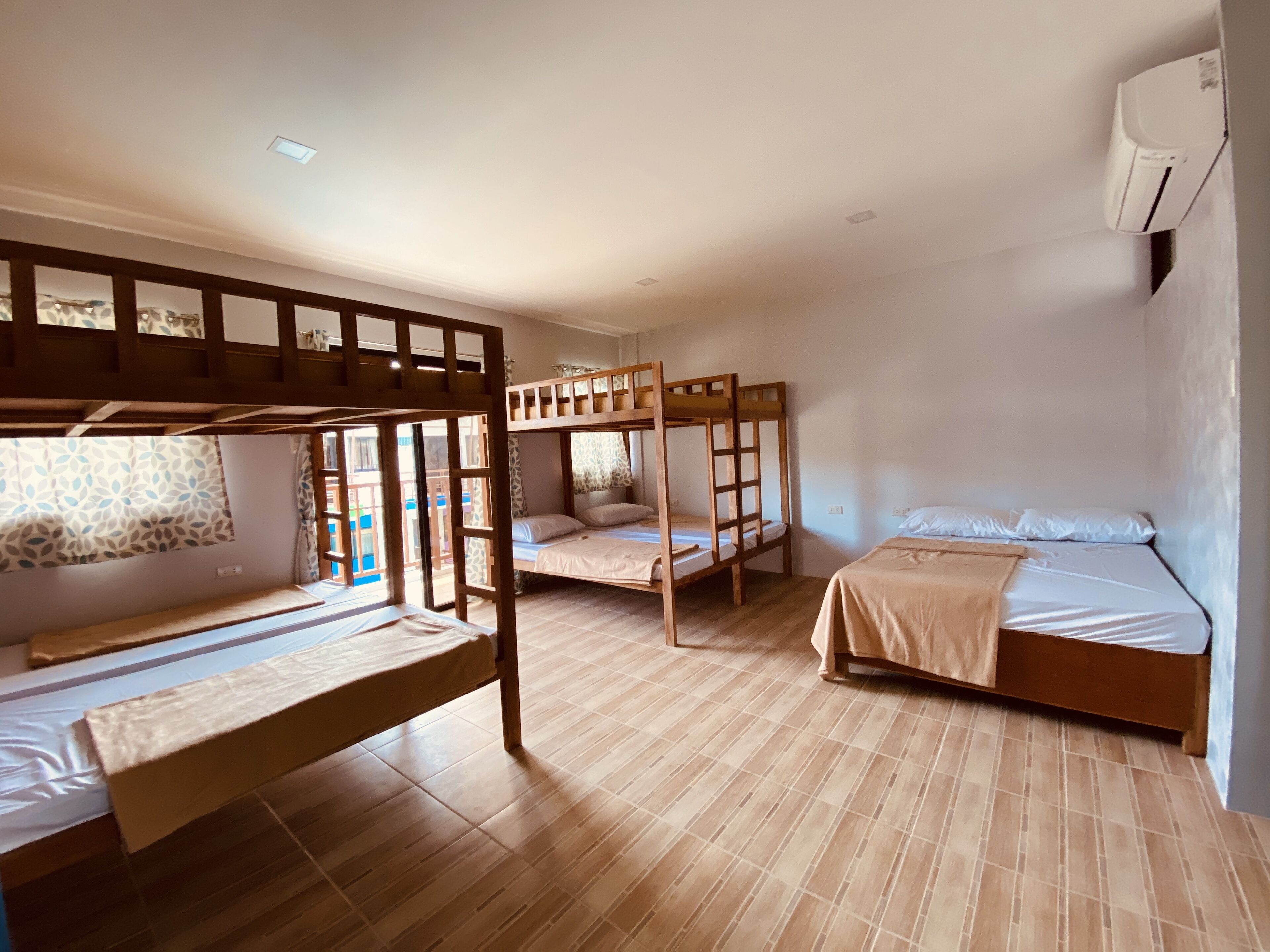 Une chambre de dortoir avec des lits superposés, un plancher en bois et un appareil de climatisation fixé au mur.