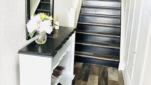 Un escalier avec des marches en bois foncé et une rampe blanche, menant à l’étage supérieur.