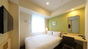 A hotel room with a bed, a desk, a chair, a television, a window, and a mirror.
