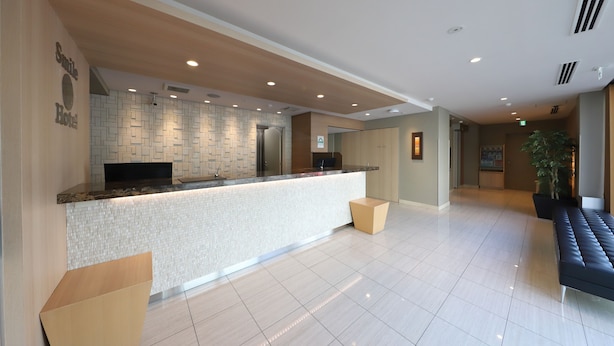 A hotel reception area with a modern design, featuring a reception desk, a seating area, and a tiled floor.