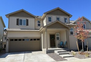 Stunning two-story home with a front entrance, porch, and garage, set amidst a beautifully maintained yard.