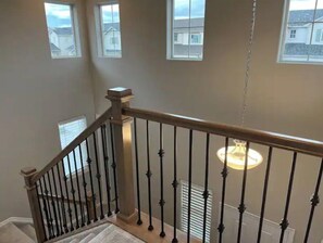 Staircase with three windows offering views of the outside, a light fixture, and a handrail.