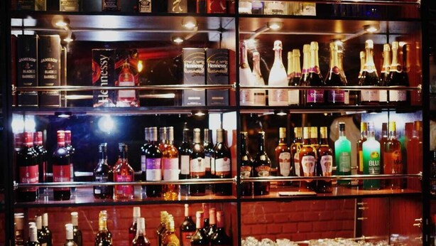 A bar with multiple shelves stocked with various liquor bottles.