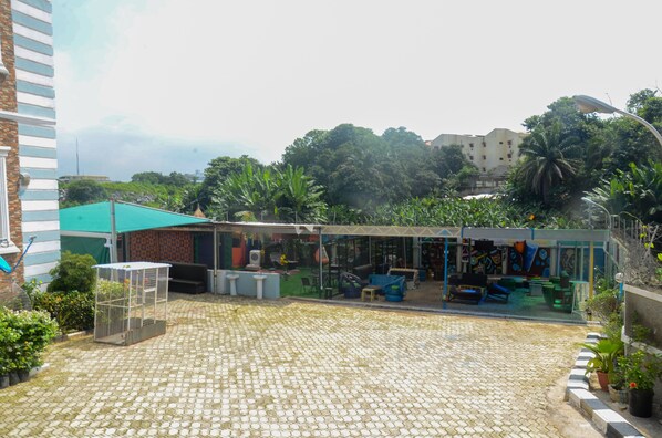 A courtyard with a covered seating area, a birdcage, and potted plants.